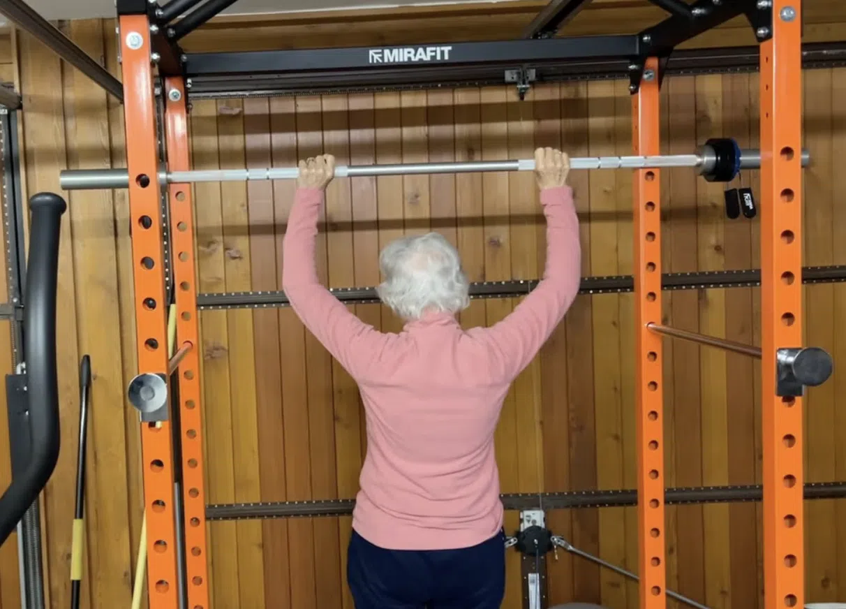 Vrouw op leeftijd doet rack press.